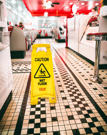 Slip and fall wet floor sign on a restaurant floor with checkered tile.