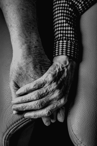 An elderly couple holding hands in black and white color photography.